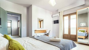 Een moderne slaapkamer met een groot bed, een spiegel, een televisie en een kledingkast.