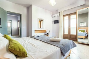 Ein modernes Schlafzimmer mit einem großen Bett, einem Spiegel, einem Fernseher und einem Kleiderschrank.