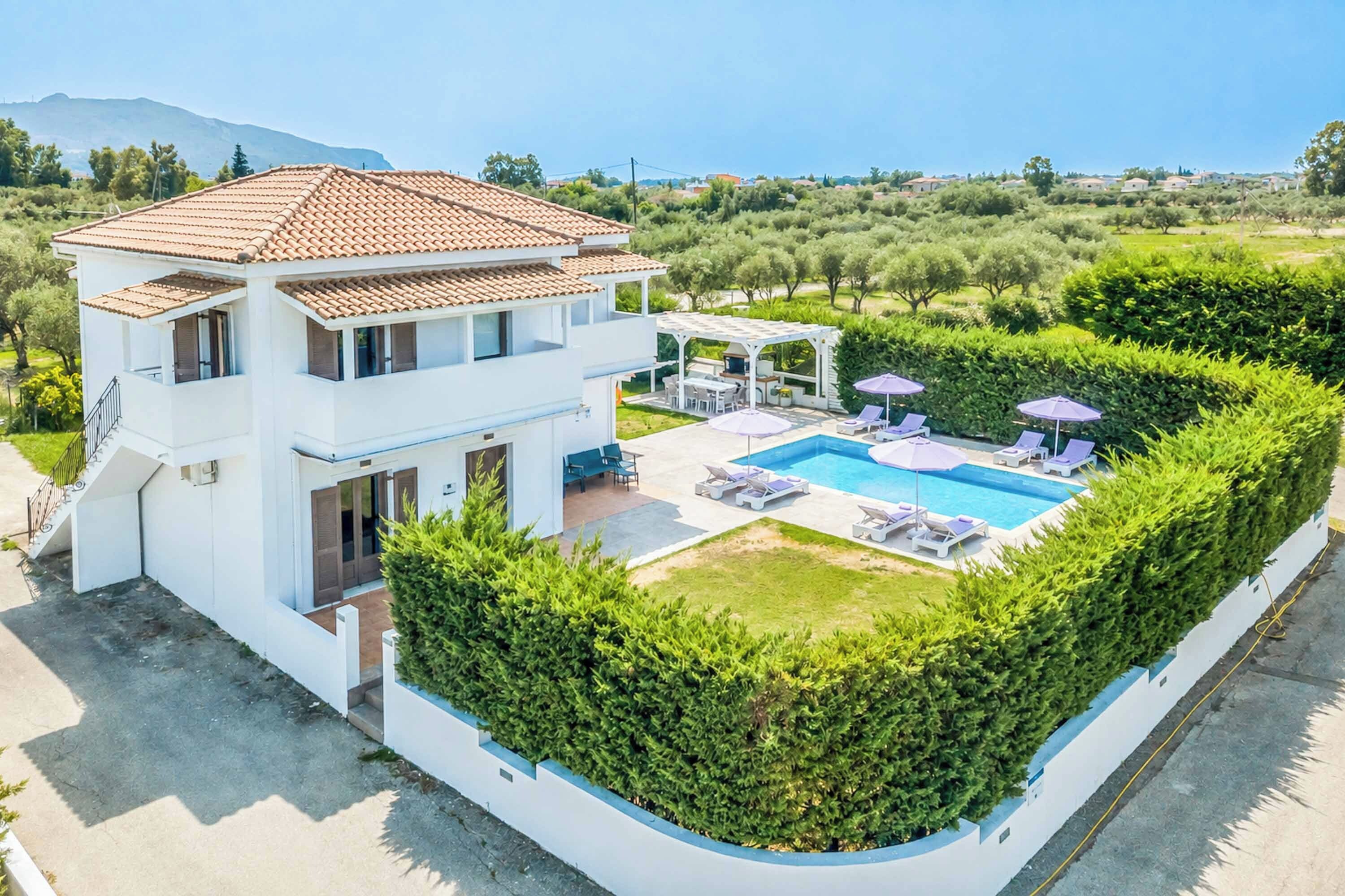 A two-story house with a swimming pool, outdoor seating, and a well-maintained garden.