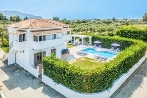 Ein zweistöckiges Haus mit Swimmingpool, Außenbereich zum Sitzen und einem gepflegten Garten.