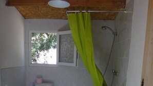 Un baño pequeño con inodoro, lavabo, ducha y un perchero verde.