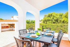 Dine al fresco in a sheltered outdoor space with a beautifully maintained garden view.