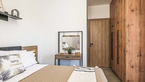 Ein Schlafzimmer mit einem Bett, einem Holzschrank, einem Nachttisch mit Spiegel und einem Regal mit Dekoration.