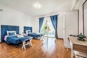 Two beds with matching bedding, a small table, and a desk with chair.