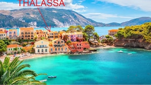 Un poble costaner amb edificis de colors i una vista clara del mar.