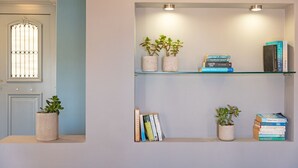 Una paret amb dues prateleires, cadascuna amb llibres i plantes en testos.