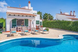 Uma área na piscina com piscina, espreguiçadeiras e uma mesa de pátio.