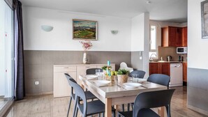 A modern kitchen with wooden cabinets, a dining table set for four, and a painting on the wall. - Villa Rachel - Three Bedroom Villa, Sleeps 6 (Es Mercadal)