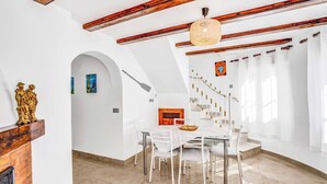 A dining area with a white table and chairs, a wooden ceiling, and a staircase leading to another level. - Villa Benicuco - Twelve Bedroom Villa, Sleeps 24 (Calp)