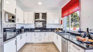A modern kitchen with white cabinets, stainless steel appliances, and a black countertop. - Villa Benicuco - Twelve Bedroom Villa, Sleeps 24 (Calp)