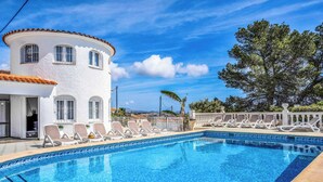 A pool with lounge chairs, a white building with a curved roof, and a clear blue sky. - Villa Benicuco - Twelve Bedroom Villa, Sleeps 24 (Calp)