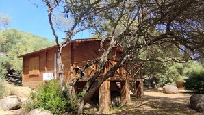 A rustic wooden cabin with a balcony, surrounded by trees and rocks. - La Tinutella 4, la tinutella (Olmeto)