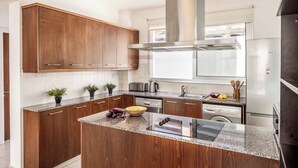 A modern kitchen with wooden cabinets, granite countertops, stainless steel appliances, and a central island.