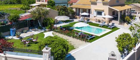 A villa with a swimming pool, outdoor seating, and a well-maintained garden.