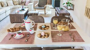 Un coin repas avec une table mise pour le petit-déjeuner, comprenant des croissants, des viennoiseries et des boissons.