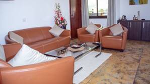 Una sala de estar con sofás de cuero, una mesa de centro de vidrio y un jarrón decorativo.