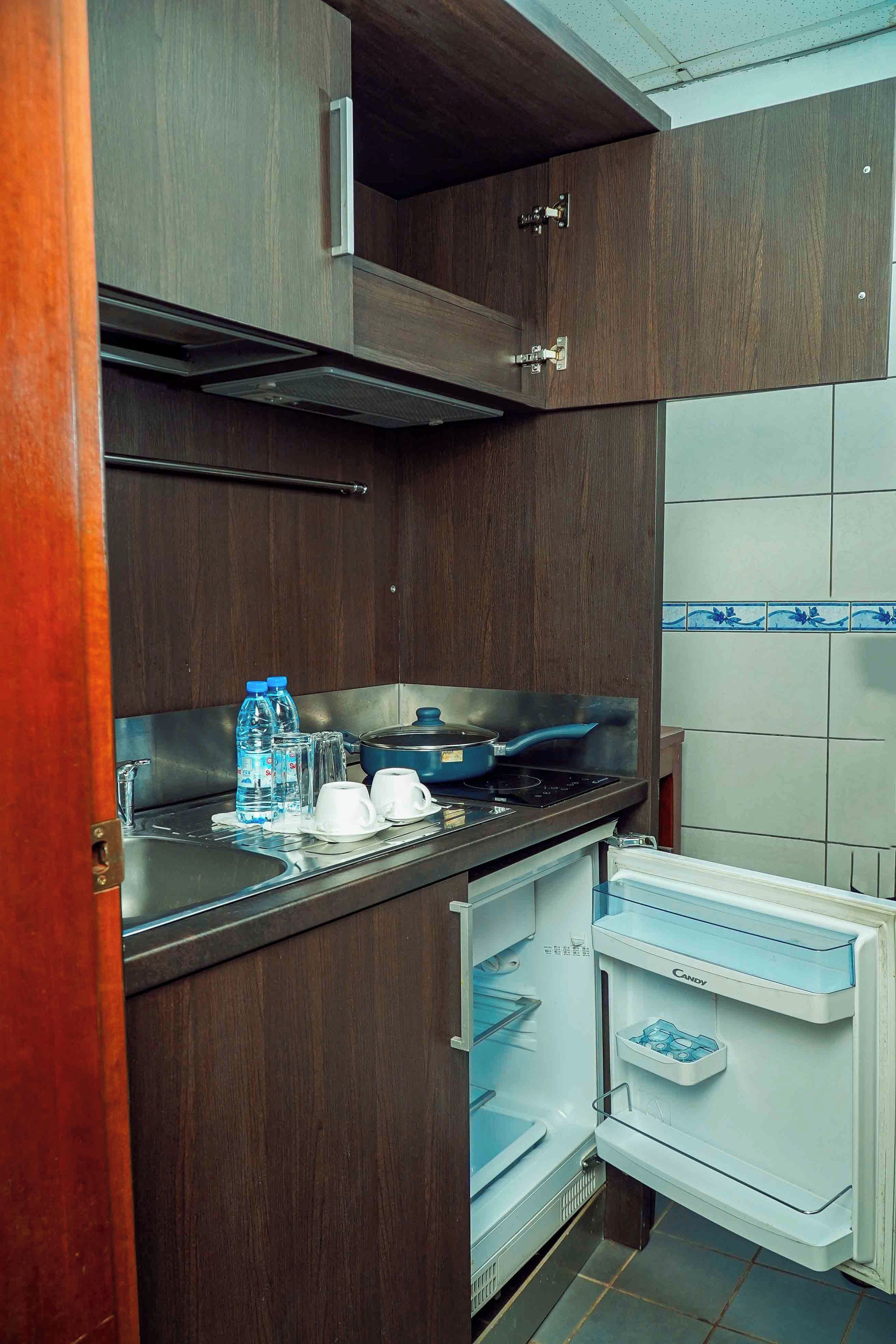 A compact kitchen with a built-in stove, a sink, and a refrigerator with a candy compartment.