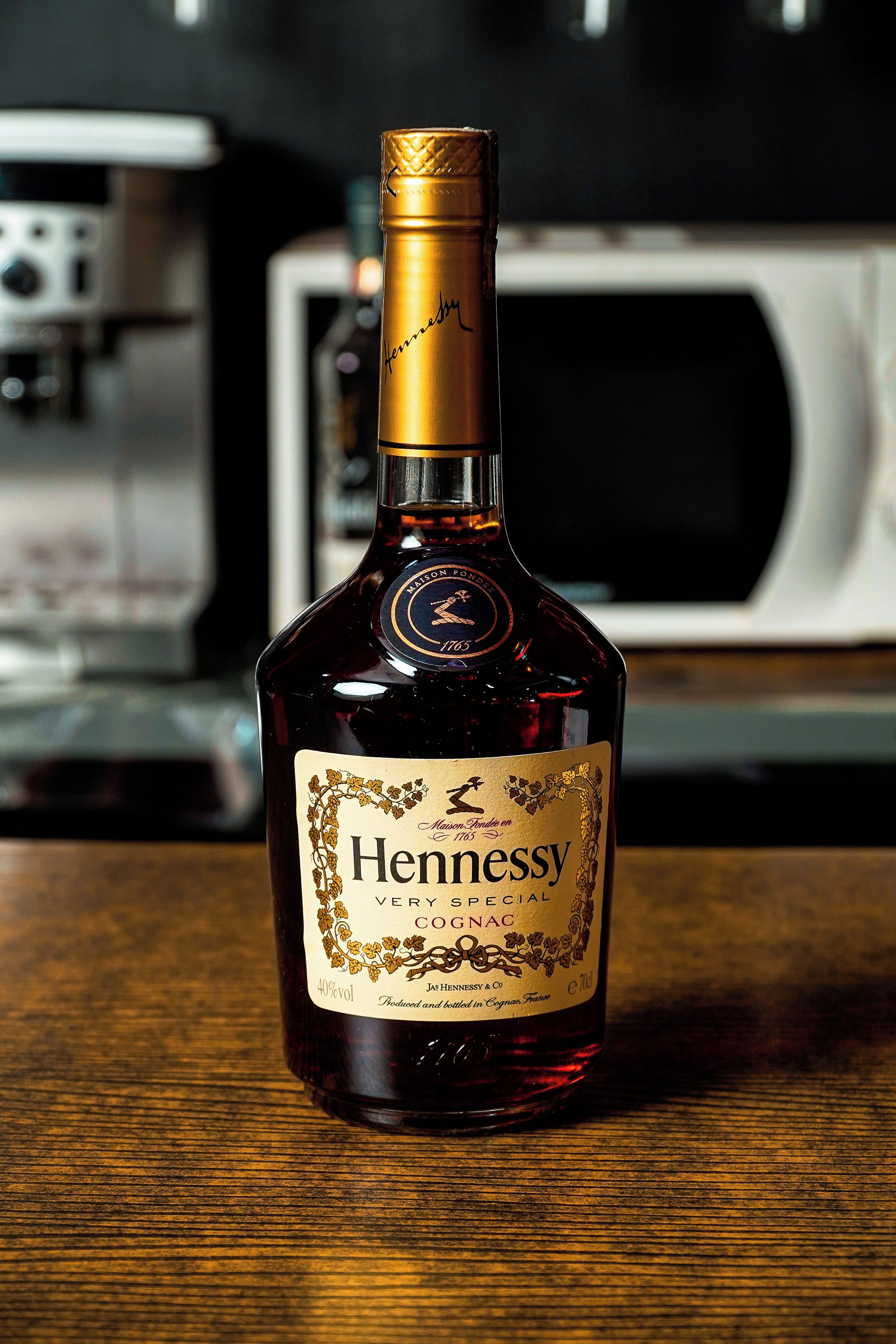 Une bouteille de cognac Hennessy posée sur une surface en bois, avec un arrière-plan flou.
