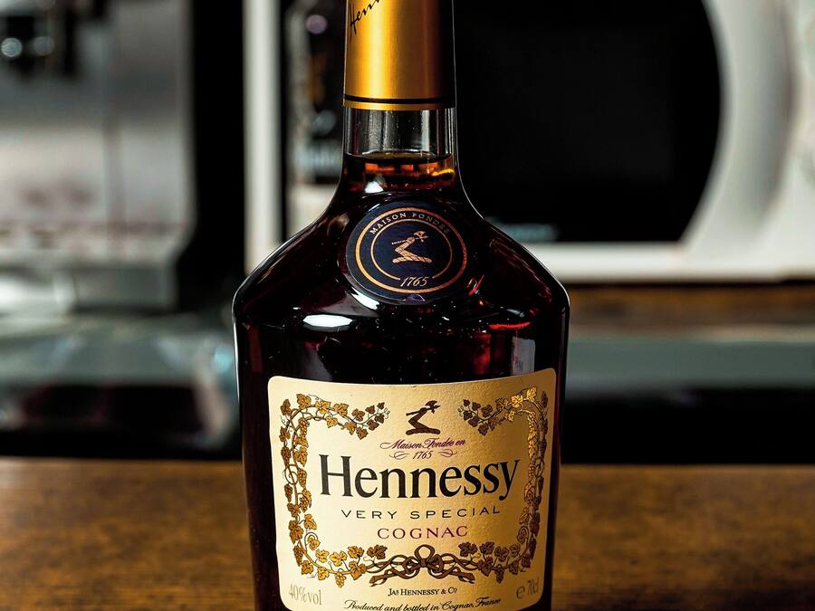 Une bouteille de cognac Hennessy posée sur une surface en bois, avec un arrière-plan flou.