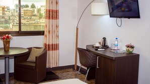 A hotel room with a desk, chair, and a TV mounted on the wall. - New Heaven Hôtel (Yaoundé)