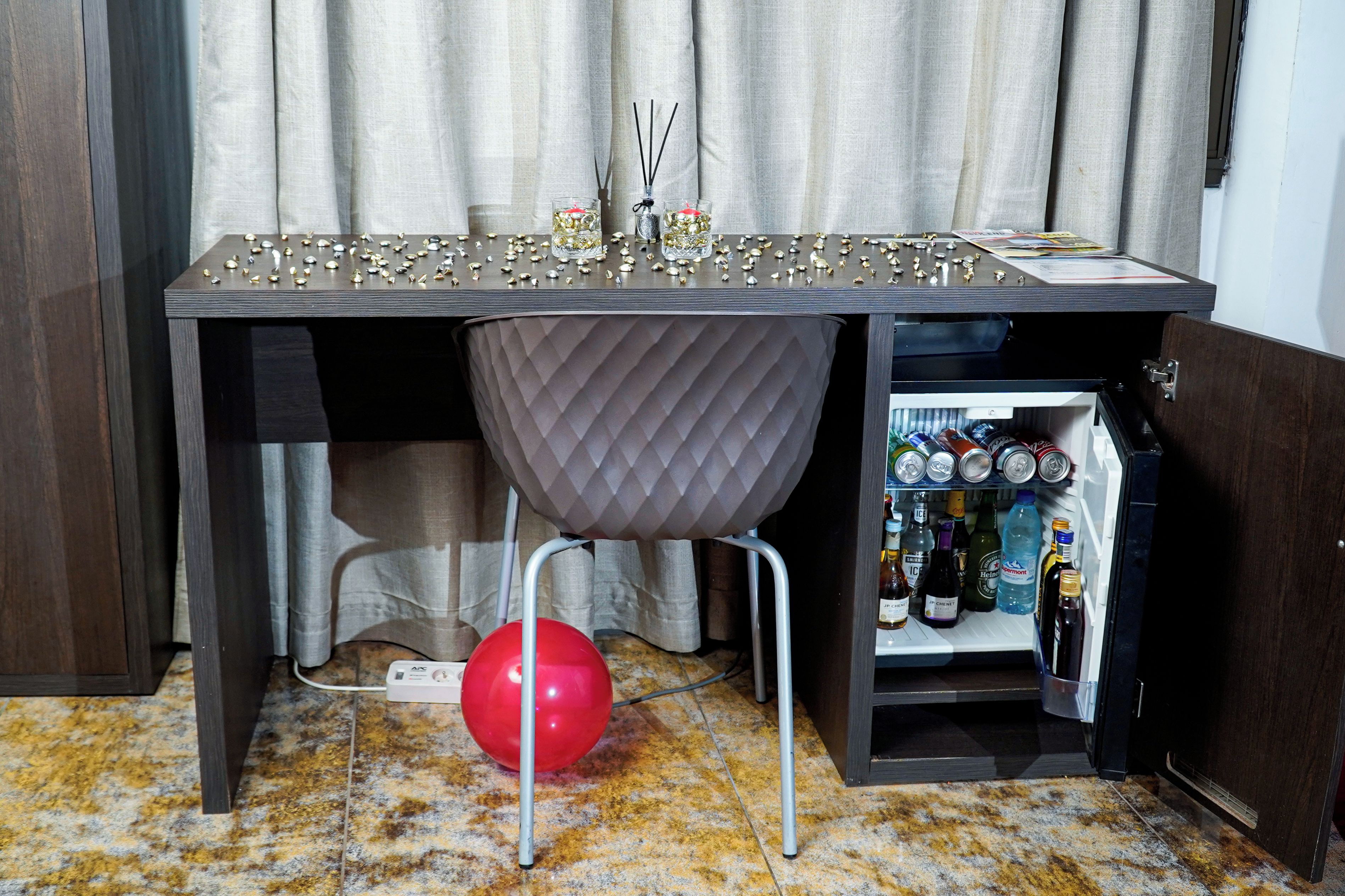 Un coin bar équipé d’un mini-bar rempli de boissons, d’un ballon rouge et d’une table agrémentée d’objets décoratifs.