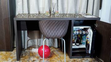Zona de bar con minibar repleto de bebidas, un globo rojo y una mesa con elementos decorativos.