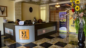 A reception desk with a checkered floor, a clock, and a decorative vase with flowers. - New Heaven Hôtel (Yaoundé)