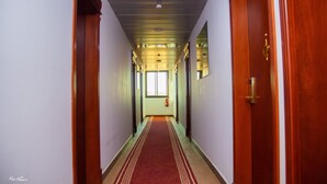 Un pasillo con alfombra roja, puertas de madera e iluminación empotrada en el techo.