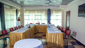 Un salón de conferencias con una larga mesa, sillas rojas y una mesa redonda.