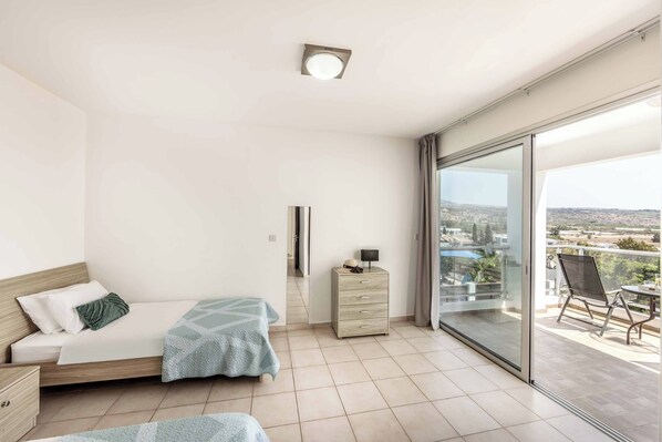 A bedroom with a bed, a dresser, and a balcony with a chair.
