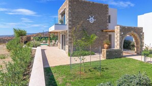 A modern house with a stone facade, a small garden, and a clear view of the surrounding landscape. - Villa Elios Residence (Rhodes)