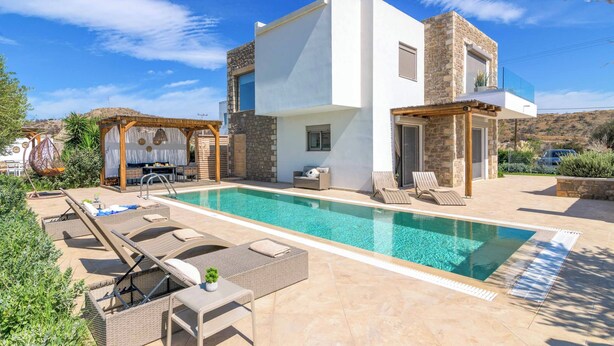 A modern villa with a swimming pool, outdoor seating, and a stone facade. - Villa Elios Residence (Rhodes)