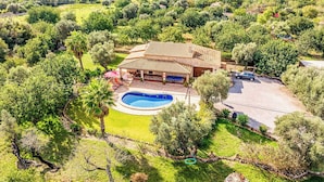 Een villa met zwembad, omgeven door weelderige begroeiing en heuvels.