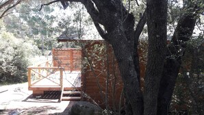 Eine Holzhütte mit einer Holzdar Terrasse und einer kleinen Treppe zu einem Schlafbereich.