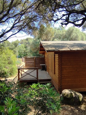 Eine Holzhütte mit einer Terrasse, umgeben von Bäumen und Pflanzen.