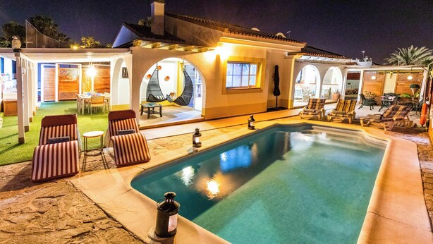Ein Schwimmbecken mit Liegestühlen und einer überdachten Terrasse.