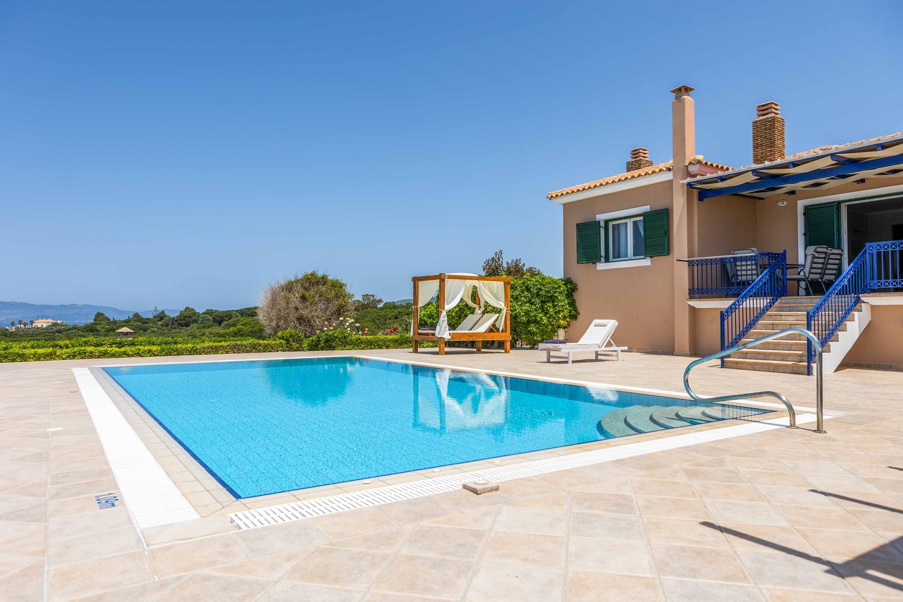 A swimming pool with a clear blue water, a wooden deck, and a building with a balcony and stairs.