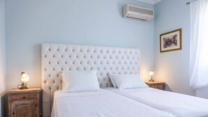 A bedroom with a tufted headboard, two bedside tables with lamps, and a framed picture on the wall. - Villa Tramonto Minies (Ionian Islands)