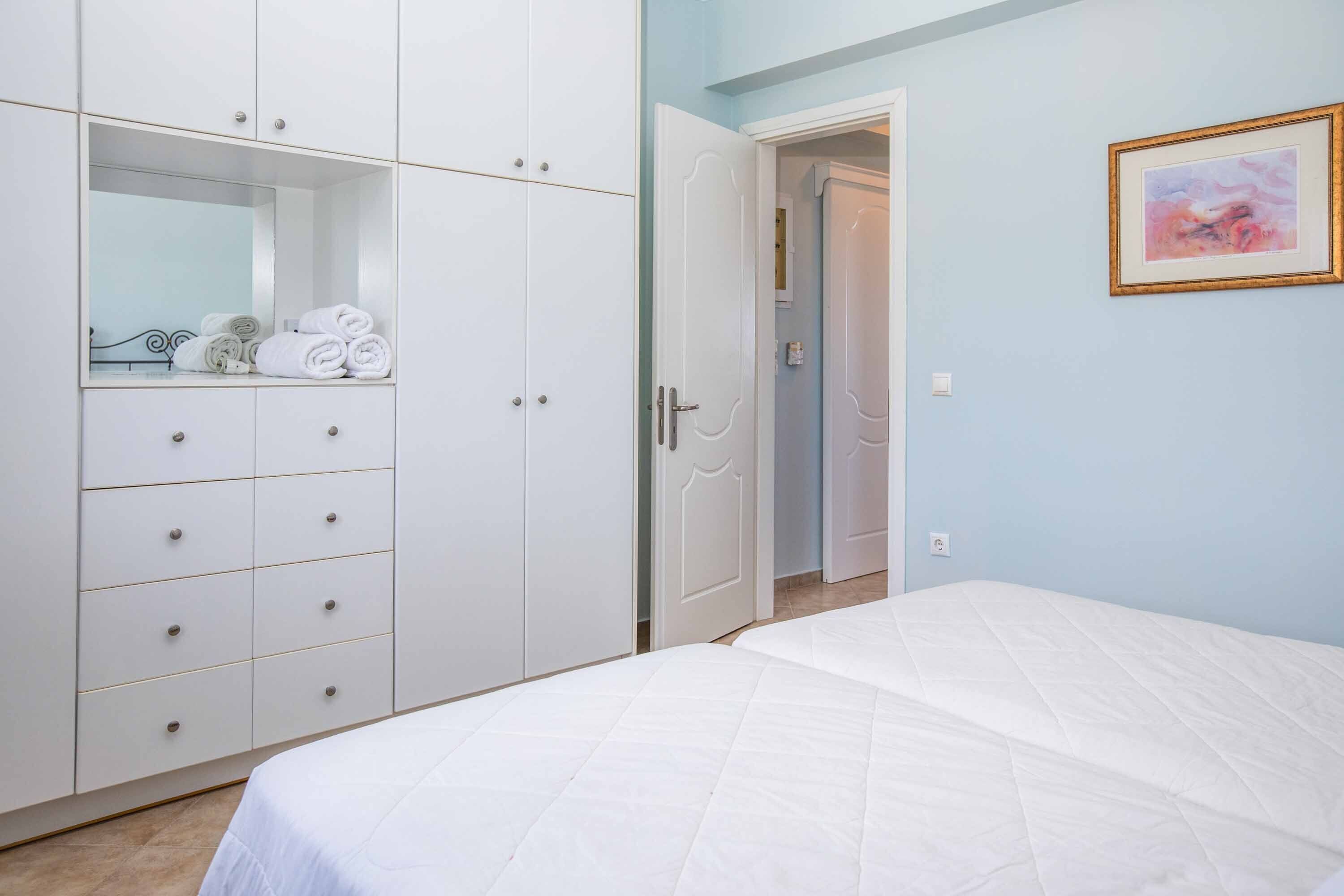 Une chambre à coucher comprenant un lit, une armoire et une porte donnant sur une autre pièce.