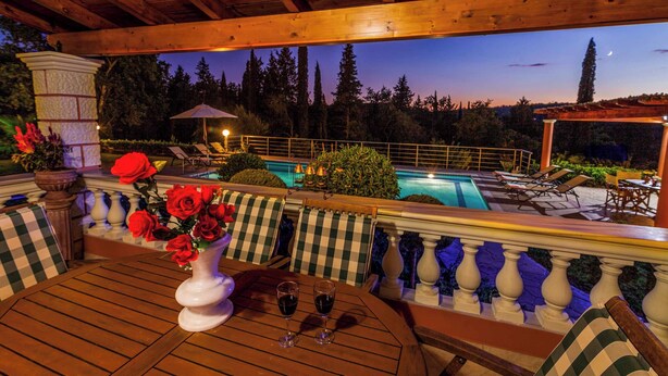 An outdoor patio with a pool, wooden furniture, and a view of the surrounding trees. - Villa Mirela Mikri - Three Bedroom Villa, Sleeps 6 (Corfu)