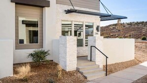 A modern house with a stone facade, a large window, and a solar panel on the roof. - The Sanctuary at Desert Color: Lagoon + Beaches (St. George)