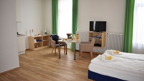 Une chambre d’hôtel comprenant un lit, un bureau avec une chaise, une télévision et un radiateur.