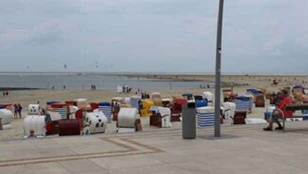 Une zone située au bord de la plage, avec différentes structures aux couleurs vives, un lampadaire et un banc.