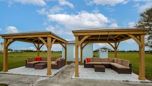Two covered outdoor seating areas with built-in sofas and tables, connected by a pathway. - New and cozy 2/1 near River (Micco)