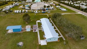 An aerial view of a campground with RVs, a large building with a blue roof, and a paved parking area. - New and cozy 2/1 near River (Micco)