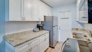 A kitchen with white cabinets, a stainless steel refrigerator, a coffee maker, and a dishwasher. - New and cozy 2/1 near River (Micco)