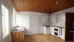 A kitchen with wooden flooring, white cabinets, a stove, and a sink. - Doe Quarry (Sheffield)