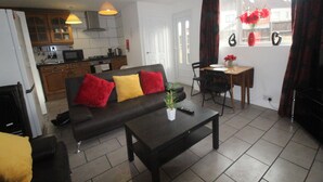 A modern living room with a sofa, a coffee table, and a dining area with a table and chairs. There is a kitchen in the background with cabinets and a microwave. - Doe Quarry (Sheffield)