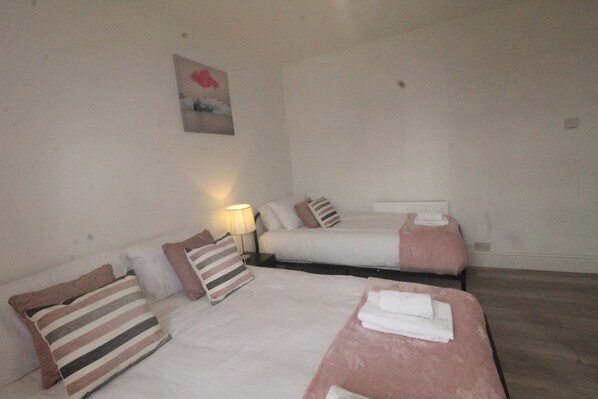 A hotel room with two beds, each with striped pillows, a bedside lamp, and a painting on the wall.
