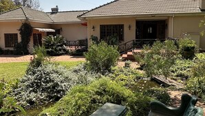 Een tweelaags huis met een pannendak en een tuin met een bankje en een kleine vijver.